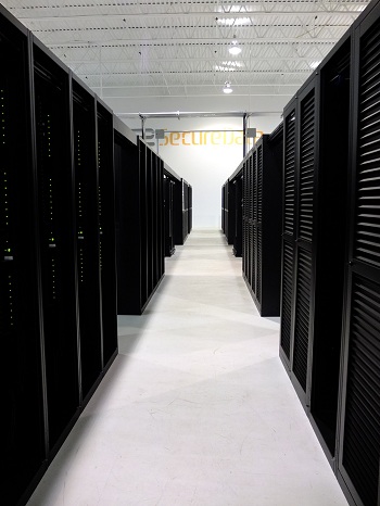 A long aisle between two rows of locked server cabinets in eSecureData DC3, with the eSecureData sign on the far wall